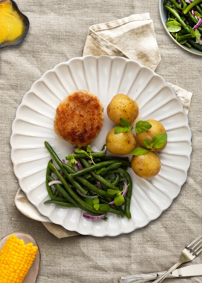 Karbonader med kartofler og smørsovs. Hertil majs og bønnesalat