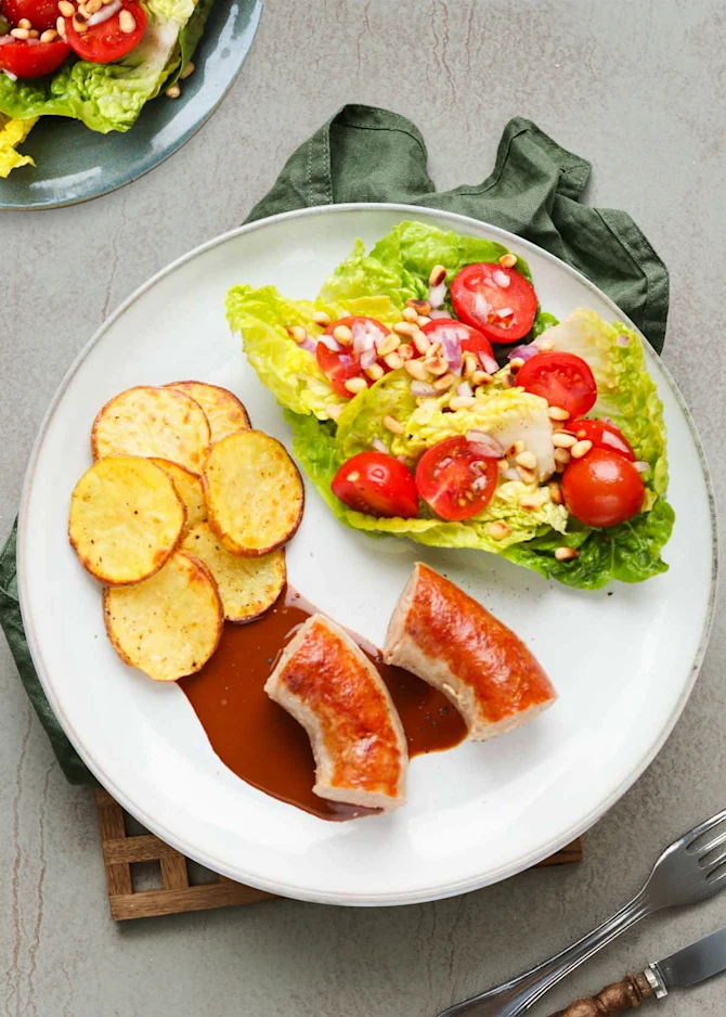 Sprødstegt medister med kartoffelskiver og sprød salat. Hertil brun sovs