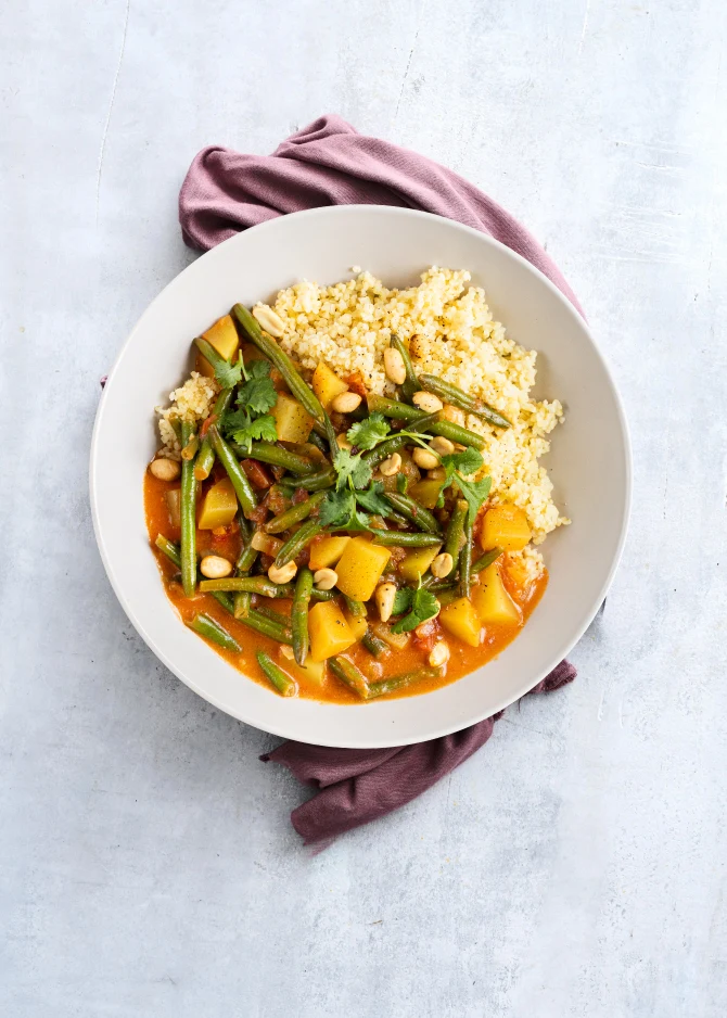 Vegetarisk gryderet med kartofler, bønner og kokosmælk. Hertil bulgur og peanuts