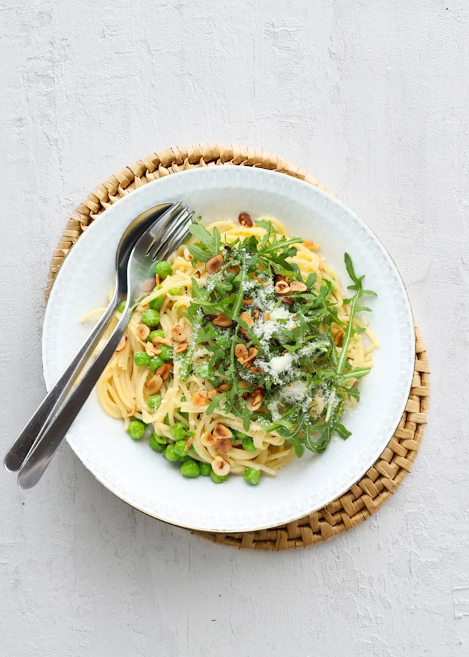 Cremet pasta med ærter, rucola og ristede hasselnødder