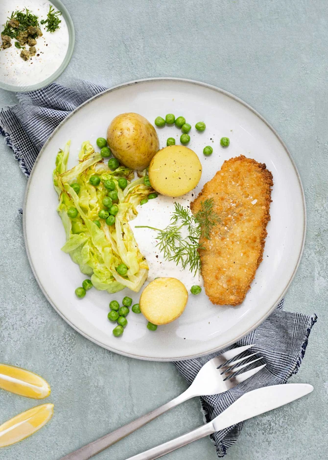 Sprøde fiskefileter med kartofler og stegt spidskål. Hertil urtedressing