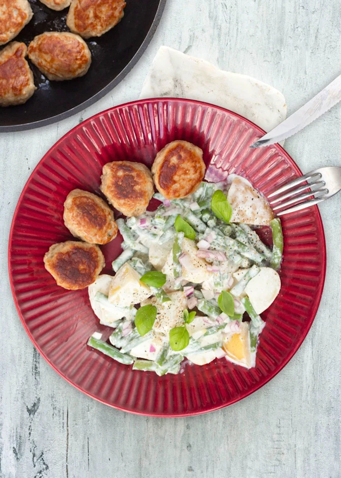 Frikadeller serveret med kartoffelsalat med hytteostcreme og bønner
