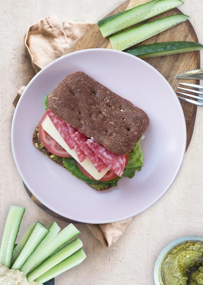 Sandwich med spansk pølse, ost og pesto. Hertil humus og gnavergrønt
