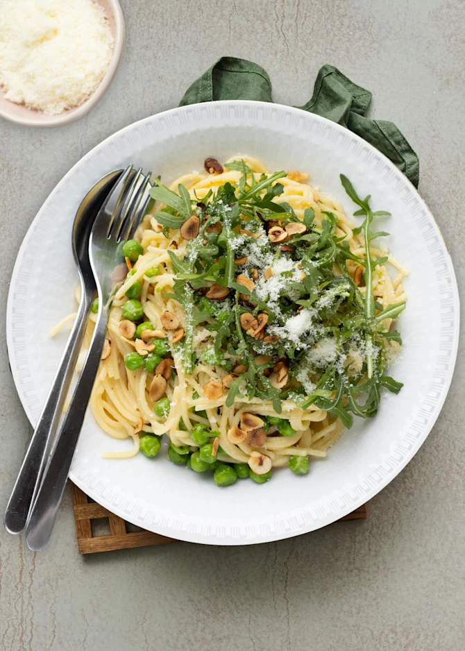 Cremet pasta med ærter, rucola og ristede hasselnødder