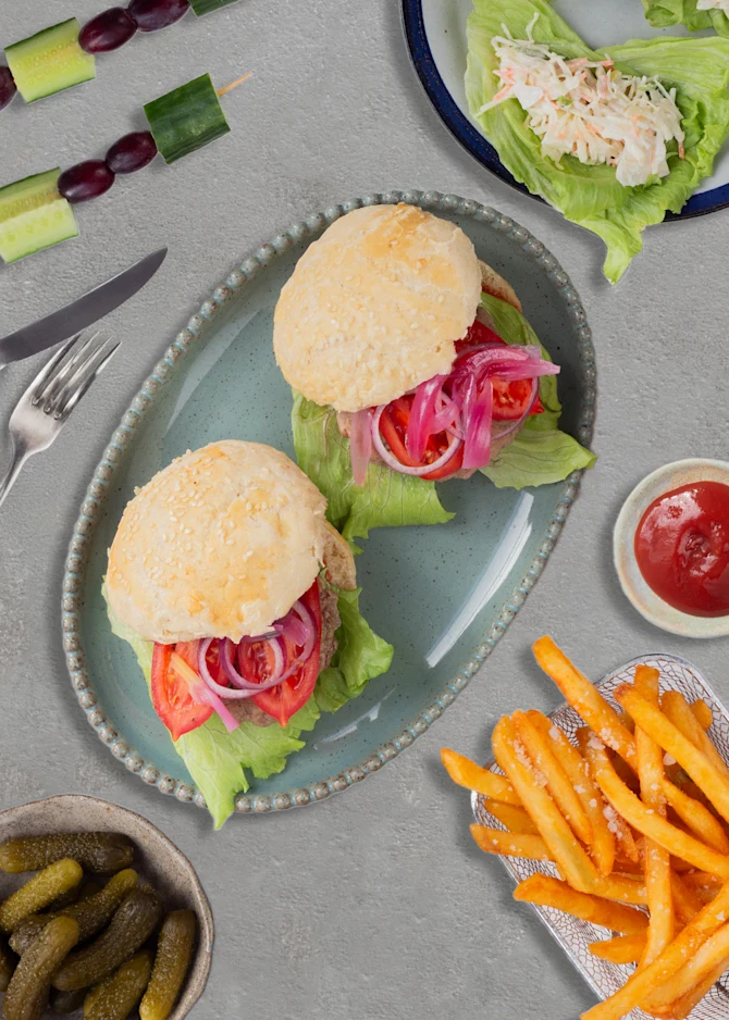 Sliders serveret med fritter, coleslaw i salatblade og grønne spyd