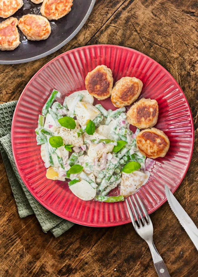 Frikadeller serveret med kartoffelsalat med hytteostcreme og bønner